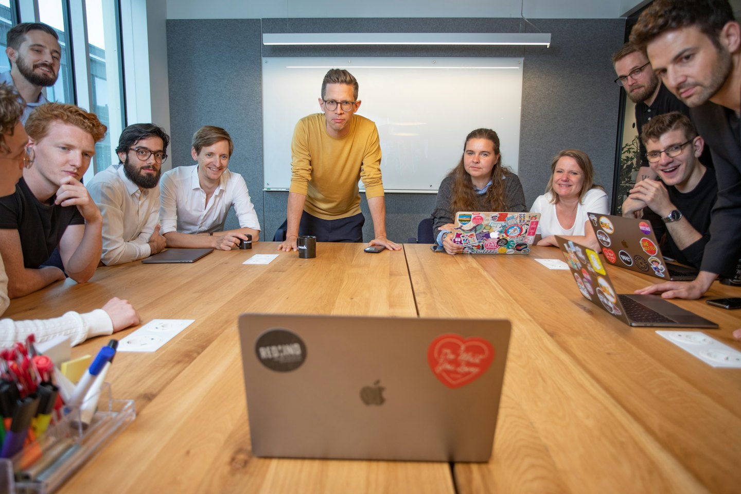 Profesionales colaboran alrededor de una mesa de madera en una oficina moderna.